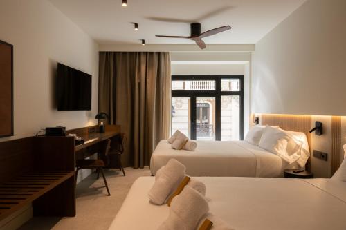 a hotel room with two beds and a desk at Moontels Colón in Valencia