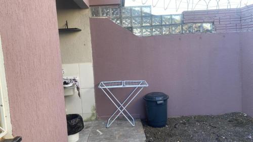a metal stand next to a purple wall with a trash can at Casa com garagem 4 pessoas in Ponta Grossa