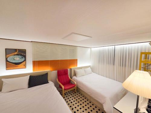 a room with two beds and a red chair at New Sale 프리미엄 대치 강남 The Premium Daechi Gangnam in Seoul