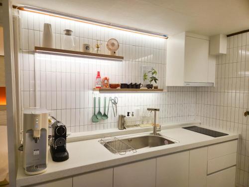 a white kitchen with a sink and a counter at New Sale 프리미엄 대치 강남 The Premium Daechi Gangnam in Seoul