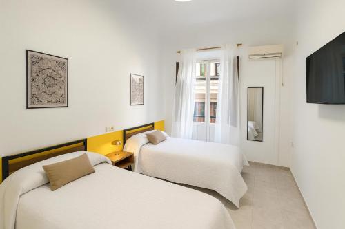 twee bedden in een kamer met witte muren bij Casa Antares in Granada
