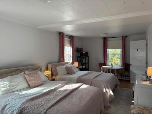 Un dormitorio con dos camas y una mesa. en Maison Charles Edmond, en Grandes-Bergeronnes