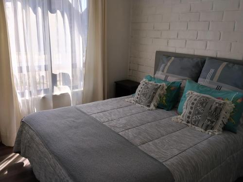 a bedroom with a large bed with pillows and a window at Casa Valle Volcanes 3 Dormitorios in Puerto Montt