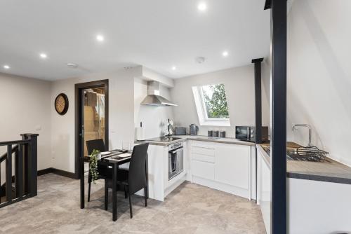 cocina con armarios blancos, mesa y comedor en Edinburgh City Penthouse Studio, en Edimburgo