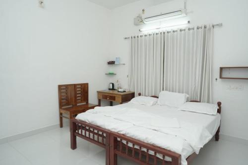 a bedroom with a bed and a table and a window at Willy's Home Stay in Parūr