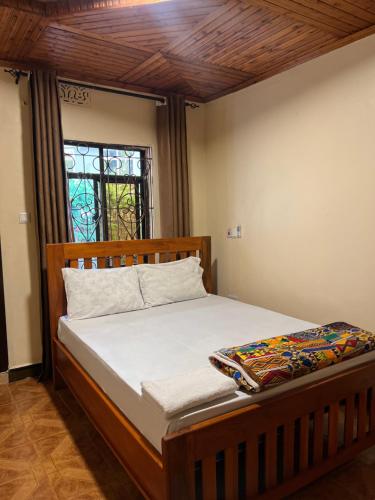 a bedroom with a wooden bed with a window at Kivuli Inn in Moshi
