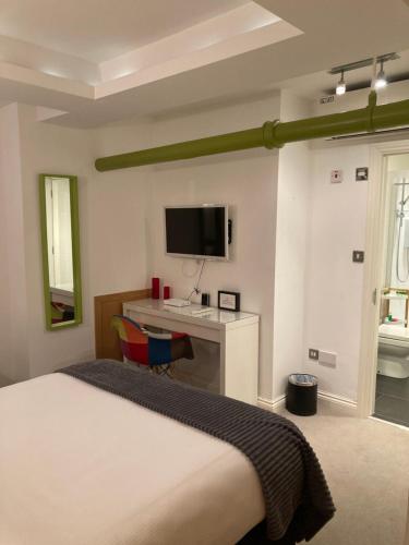a bedroom with a bed and a desk and a tv at NELL GWYNN HOUSE - Hotel Room Style POD Room 61 in London