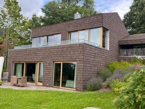 a brown brick house with glass doors on a yard at Riverside Architect-Designed Garden Apartment in Süderstapel