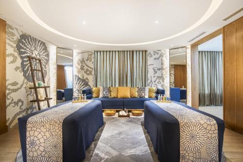 a room with two tables and a blue couch at Amari Johor Bahru in Johor Bahru