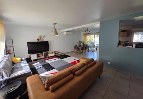 een woonkamer met een bank en een tv bij Villa - Le Nids sur Orge in Villiers-sur-Orge