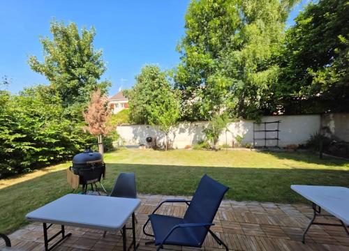 een achtertuin met een grill en tafels en stoelen bij Villa - Le Nids sur Orge in Villiers-sur-Orge