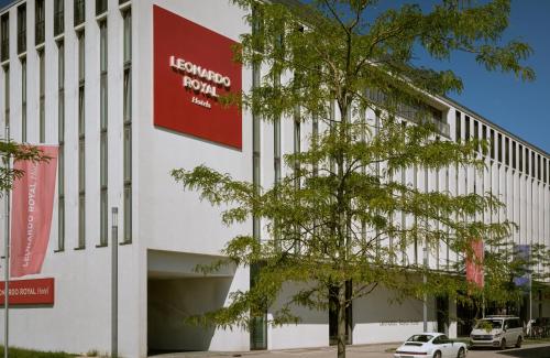 a white building with a red sign on it at Leonardo Royal Hotel Munich in Munich