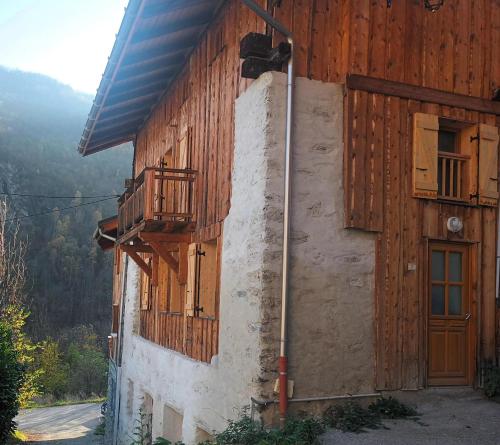 ein Holzgebäude mit einer Tür und einem Balkon in der Unterkunft Chalet La Landonne chaleureux pour 2 in La Combe