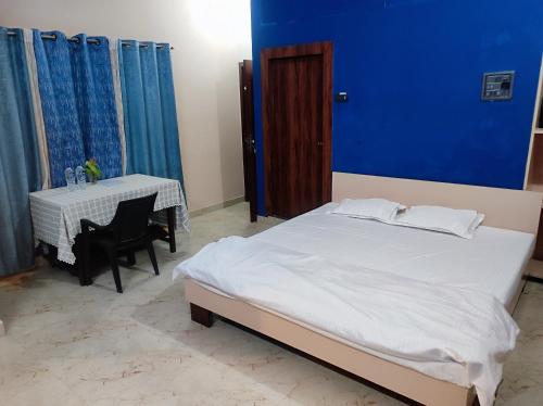 een slaapkamer met een bed met een tafel en een blauwe muur bij GoFam in Dibrugarh