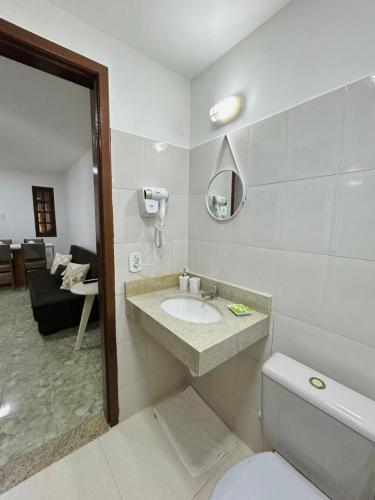a bathroom with a sink and a toilet and a couch at Búzios Apartamento Charmoso in Búzios