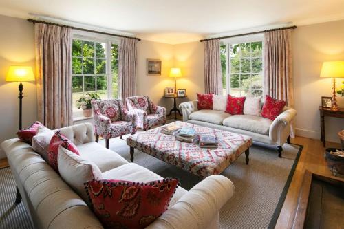 a living room with white couches and red pillows at Butley Priory Farmhouse 12 in Woodbridge