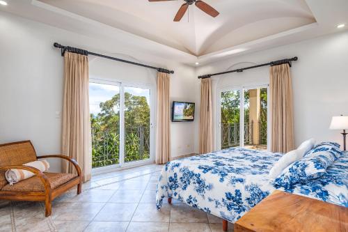 um quarto com uma cama, uma cadeira e janelas em Beautiful Ocean View Condo Steps To The Beach em Tamarindo