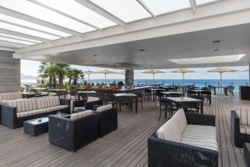 a patio with tables and couches and chairs and the ocean at Pestana Madeira Beach Club in Funchal