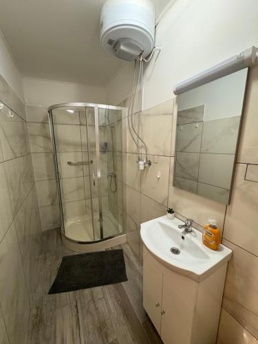 een badkamer met een wastafel, een douche en een spiegel bij Amicii apartman in Makó