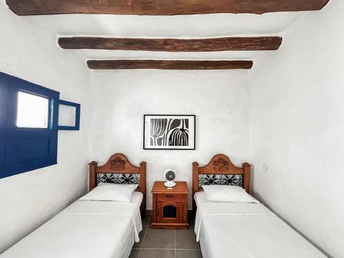2 Betten in einem Zimmer mit weißen Wänden und Holzdecken in der Unterkunft Unique House Elena Barichara Open Space Bright in Barichara