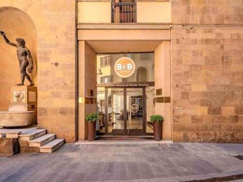 a entrance to a building with a statue in front at B&B Hotel Firenze Pitti Palace al Ponte Vecchio in Florence