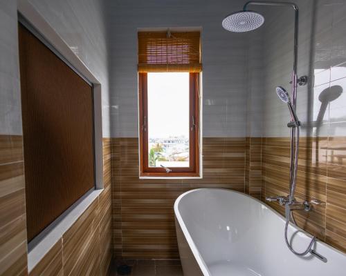 une salle de bain avec une baignoire et une fenêtre dans l'établissement Homestay Gio bien, à Ấp Ngọc Hải