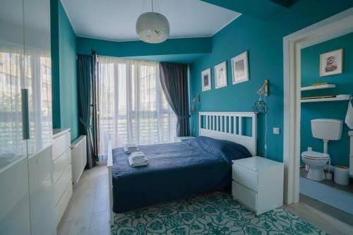 a blue bedroom with a bed and a toilet at Homey Apartment Obor in Bucharest