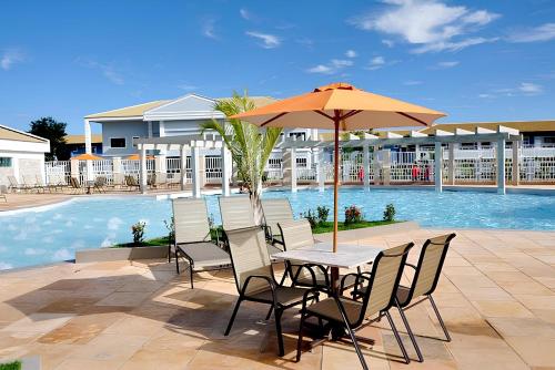 a table and chairs with an umbrella next to a pool at Resort Internacional DiRoma in Caldas Novas