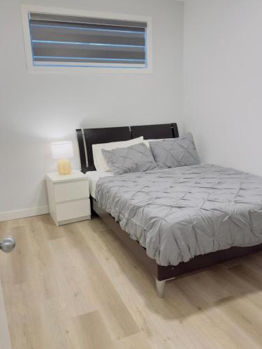een slaapkamer met een bed met een nachtkastje en een raam bij Modern Comfort West Edmonton in Edmonton