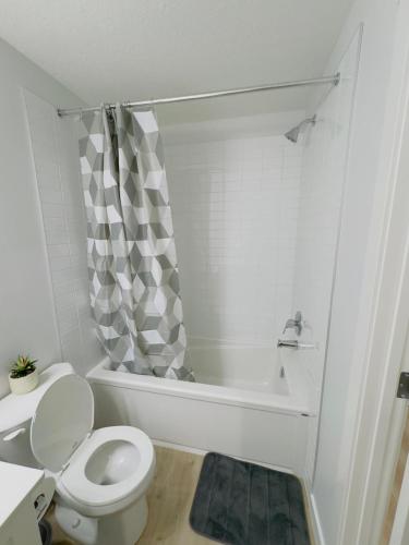 een witte badkamer met toilet en ligbad bij Modern Comfort West Edmonton in Edmonton