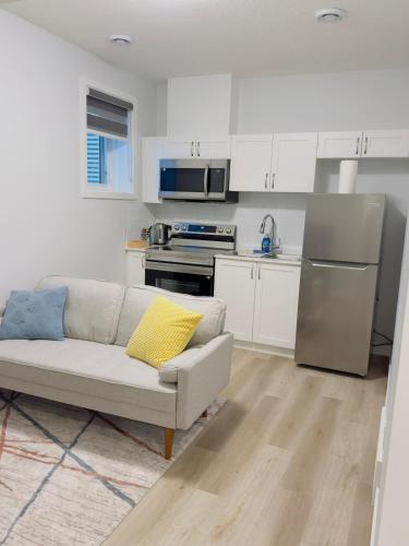 a living room with a couch and a kitchen at Modern Comfort West Edmonton in Edmonton
