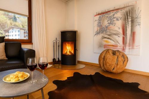 a living room with a fireplace and two glasses of wine at KITZHORN EMOTIONS near skilift by Belle-Stay in Jochberg