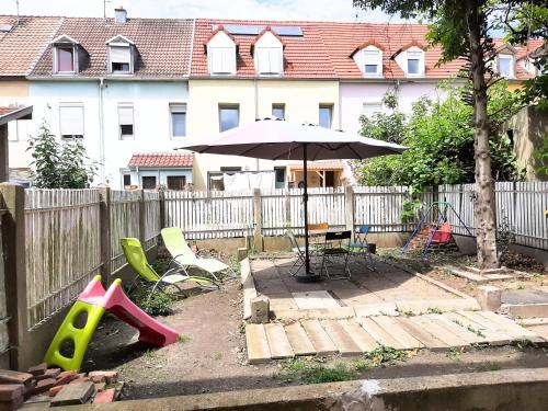 een achtertuin met een parasol en een tafel en stoelen bij L'Échappée douce - Central, paisible et lumineux in Mulhouse