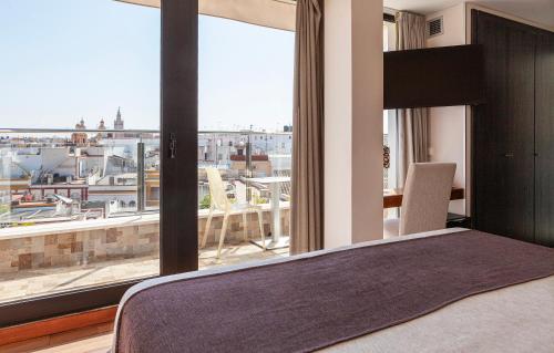 a bedroom with a bed and a large window at Hotel Don Paco in Seville