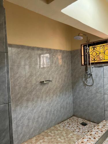 a bathroom with a shower with a glass door at Kivuli Inn in Moshi