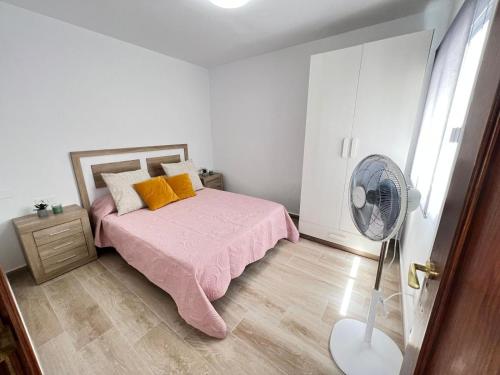 a bedroom with a pink bed and a fan at Precioso Atico Vista Teide in Las Galletas