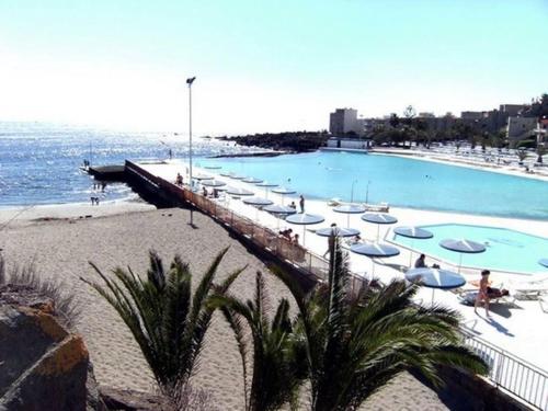 a large swimming pool with umbrellas and the ocean at Precioso Atico Vista Teide in Las Galletas