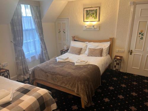 a hotel room with a bed with two towels on it at The Beaumont in Sittingbourne