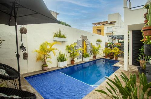 a swimming pool with potted plants and an umbrella at Casita El Nido- Spacious 2 Bedroom Main Floor Apartment in Bucerías