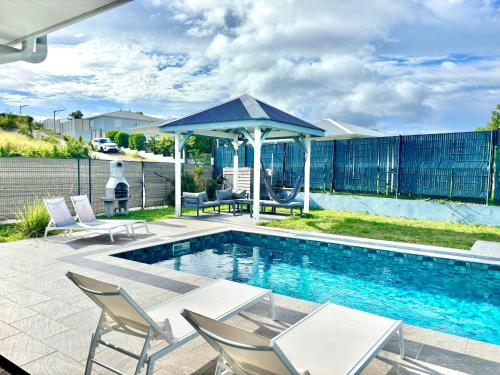 a swimming pool with chairs and a gazebo at Chez Valérie et Patrick in Le Diamant