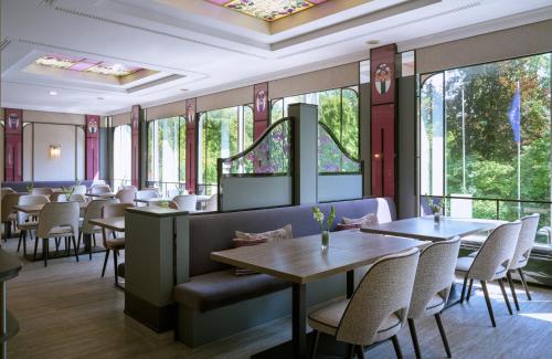 Un restaurante con mesas, sillas y ventanas. en Leonardo Hotel Munich Arabellapark, en Múnich