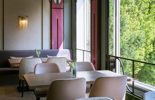 una habitación con mesas y sillas y una ventana grande en Leonardo Hotel Munich Arabellapark, en Múnich