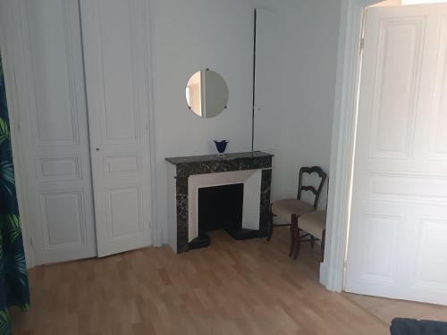 une pièce blanche avec une cheminée et un miroir dans l'établissement COURS LA VILLE, à Cours-la-Ville