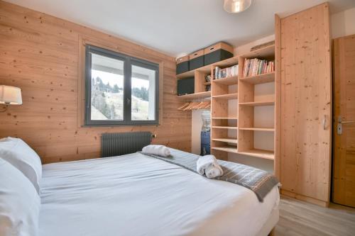 Un dormitorio con una cama y estanterías. en Les Perralpes 2, en Le Grand-Bornand