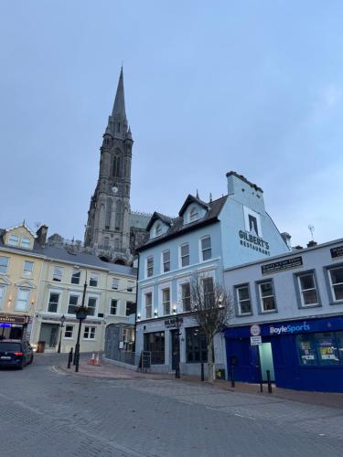 a group of buildings on a street with a clock tower at Gilberts Townhouse in Cobh