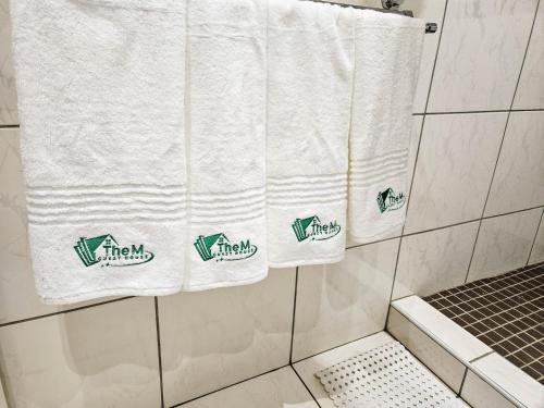 a bathroom with white towels hanging in a shower at The M GuestHouse in Kempton Park