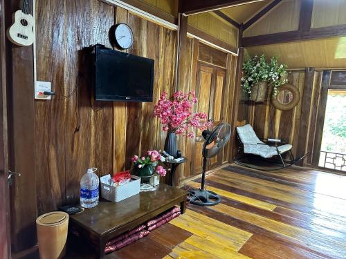 a living room with a tv and a wooden wall at The Bare Nest Retreat in Làng Lai