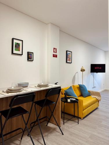 a living room with a yellow couch and a table at Color Avenida T0 in Águeda