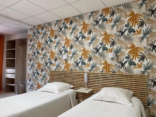 two beds in a bedroom with a floral wallpaper at Hôtel La Vigneraie in Levens