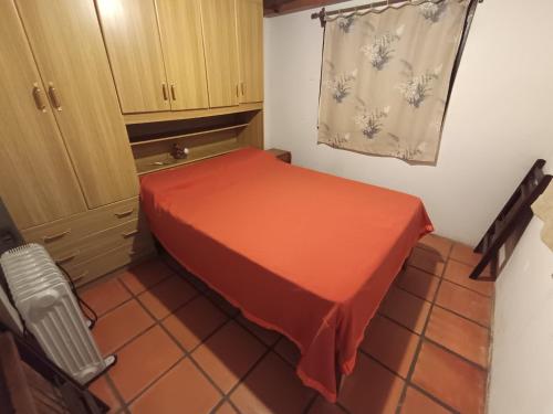 Casa Quincho en el Bosque في بونتا دل إستي: غرفة صغيرة مع سرير احمر وخزانة